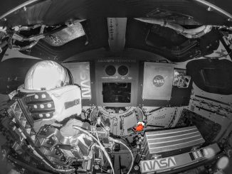 Scientific illustration: a B&W image of the interior of a spacecraft and an astronaut, with a small, orange item floating in midair off to the middle right - a tiny Snoopy doll used to measure relative weightlessness inside the cabin.