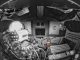 Scientific illustration: a B&W image of the interior of a spacecraft and an astronaut, with a small, orange item floating in midair off to the middle right - a tiny Snoopy doll used to measure relative weightlessness inside the cabin.