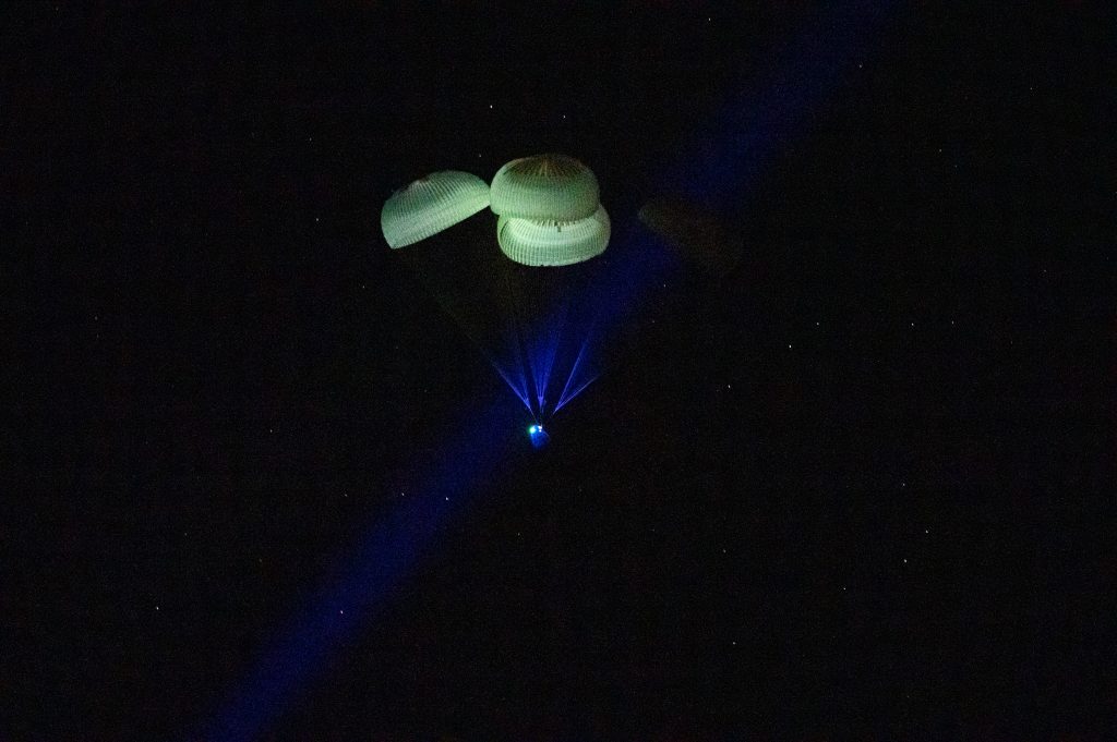 Scientific illustration of a space capsule landing on water, photographed by NASA/Keegan Barber.