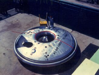Scientific illustration of an Avrocar, a silver, disc-shaped aerial vehicle, gleaming steel and black vents, parked outside a shaded hangar.