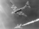 Scientific illustration of a supersonic rocket plane being launched from a bomber, a black-and-white photo of a shining steel dart leaving a trail of cloud beneath the massive shadow of its mothership.