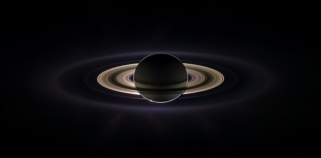 Scientific illustration of Saturn eclipsing the sun, a dramatic image of the ringed planet backlit in space.
