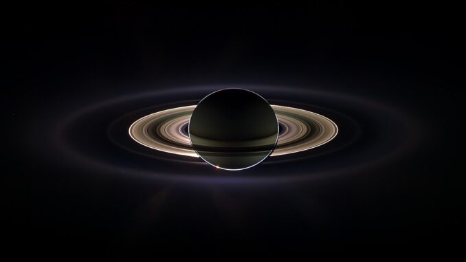 Scientific illustration of Saturn eclipsing the sun, a dramatic image of the ringed planet backlit in space.