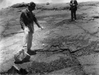 Scientific illustration of the aftermath of a volcanic eruption, with a man in a suit standing beside a large rock, apparently holding his arms out for scale. Such was science in 1925.