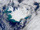 Scientific illustration of the surface of the Earth; a colorful satellite picture of stark-white Iceland in the blue-green North Atlantic.