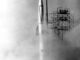 Scientific illustration of a rocket launching in the 1950s, metal scaffolding and exhaust clouds, a white tower rising skyward, gleaming in black and white.